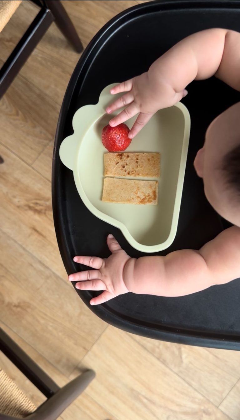 Baby eating solid food at highchair